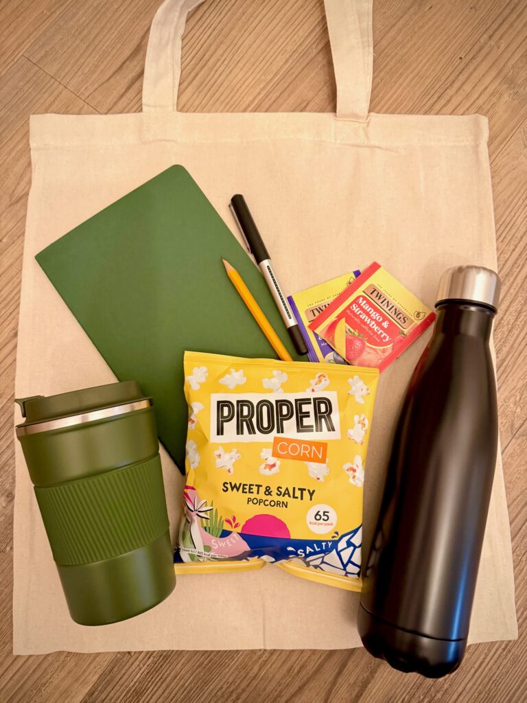Tote bag with a water bottle, coffee cup, popcord, pad and pen
