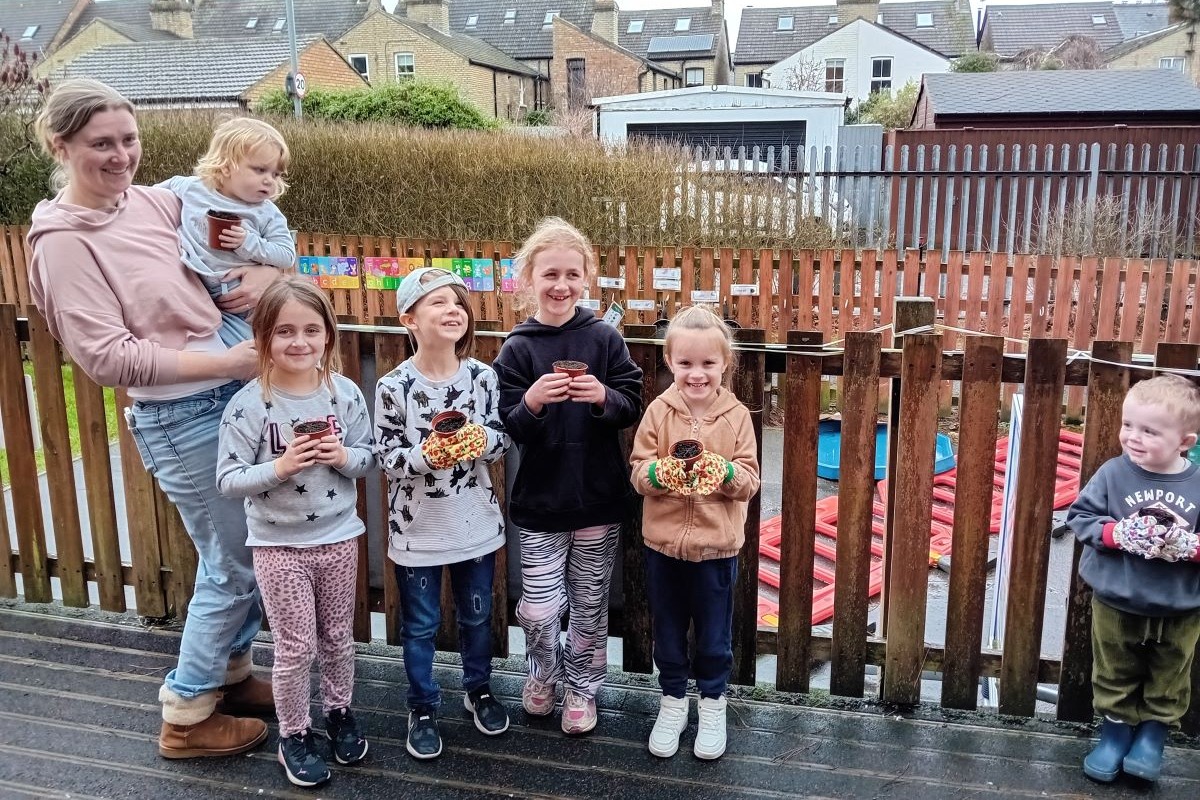 Children holding plant pots smiling