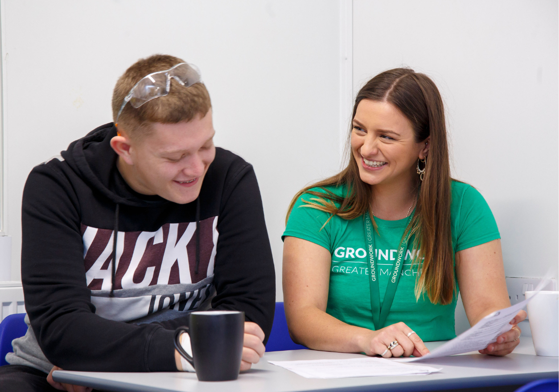 Young man sat at a desk receiving employment advice from a female employment adviser