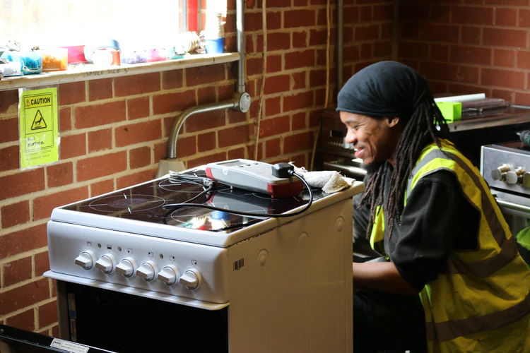 REWORK engineer repairing a electric cooker, smiling