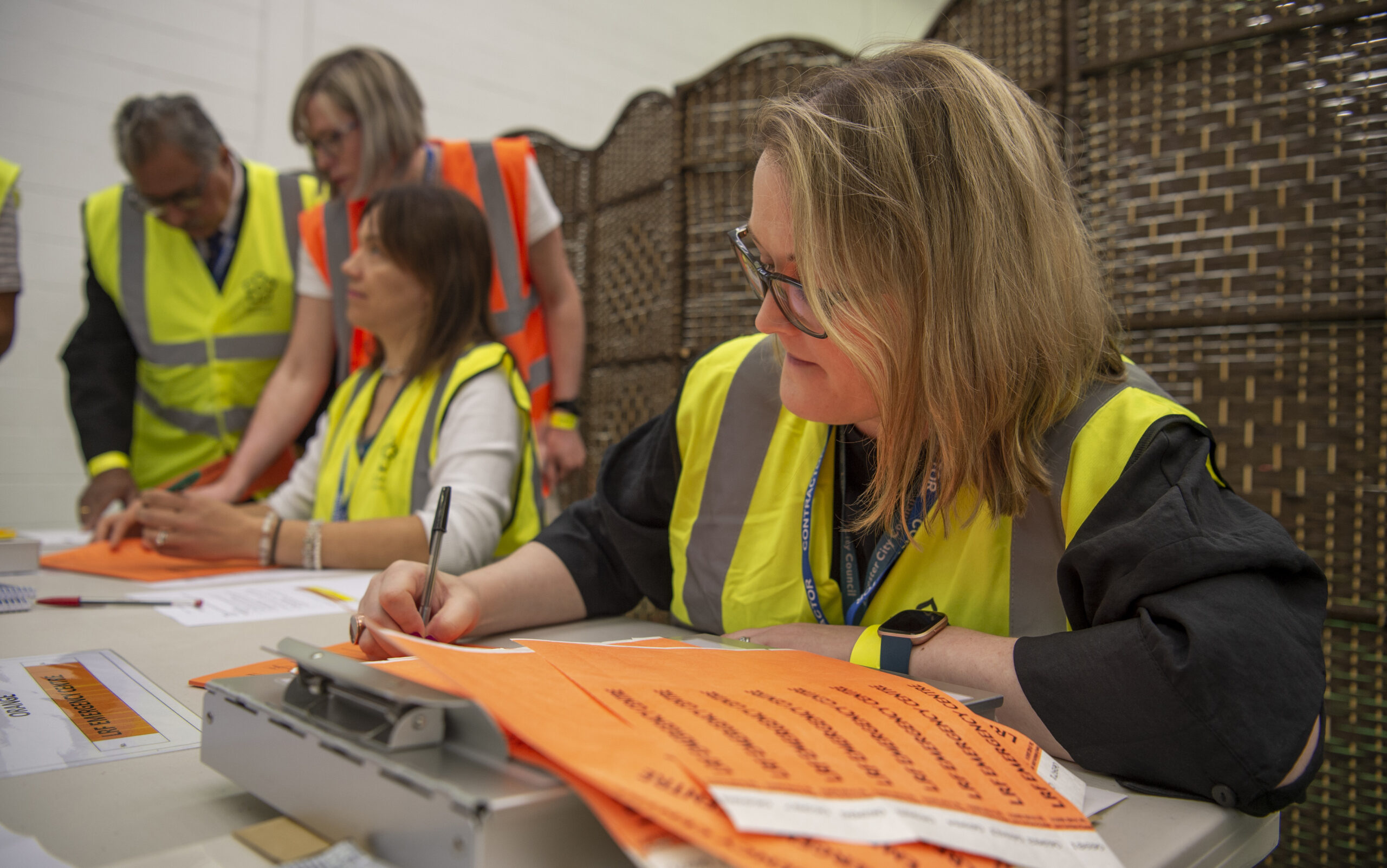 Photo of people wearing yellow and orange high visibility vests.