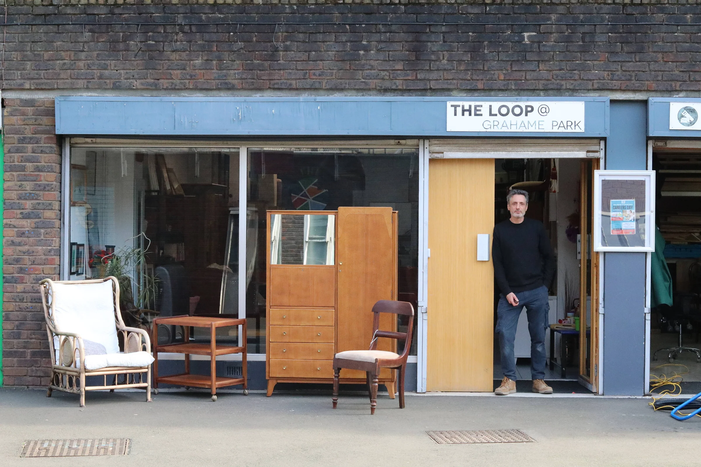 The Loop at Grahame Park window with second-hand furniture outside on a sunny day.