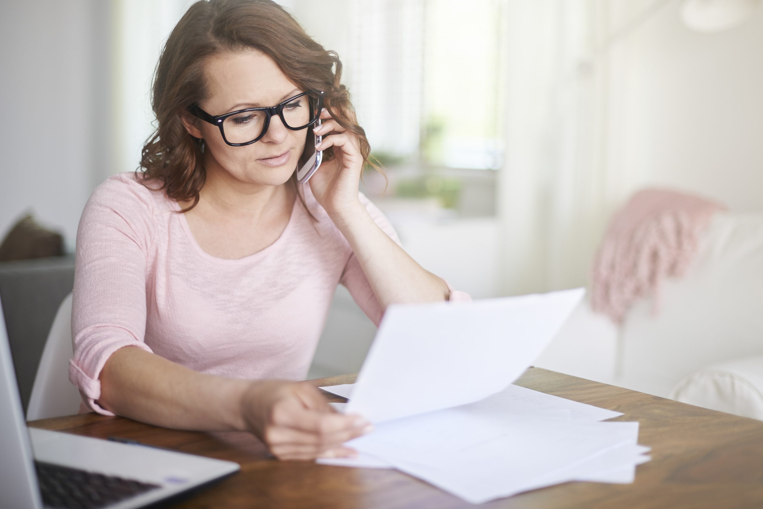 Woman on phone, looking at paperwork