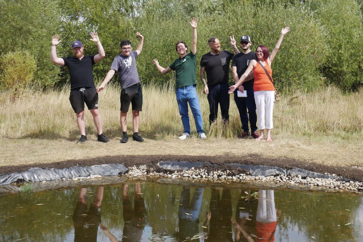 Project particiapnts waving near the pond they made