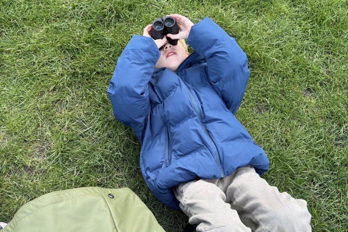Child lying on the ground looking through binoculars