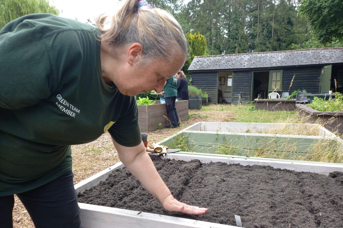 Volunteer with hands on soil in a garden