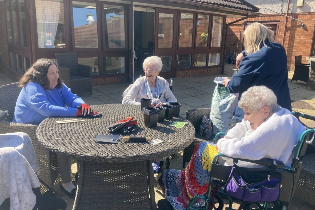 Care home residents enjoying planting seeds outside
