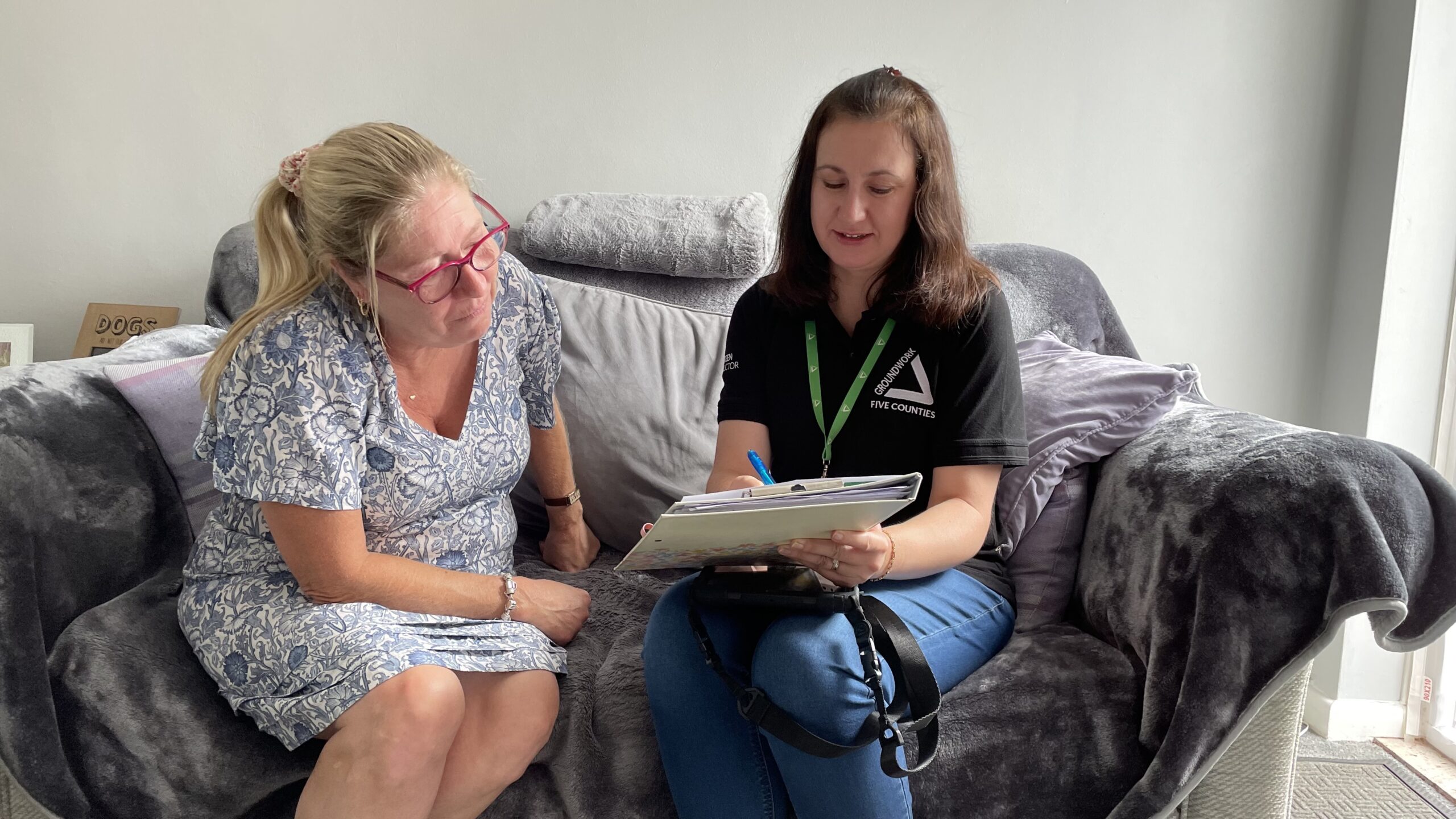 Two women sitting on sofa with paperwork.