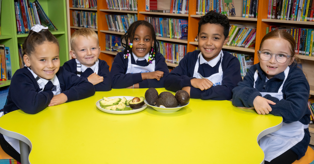 School Children sat in front of cut up avocados smiling