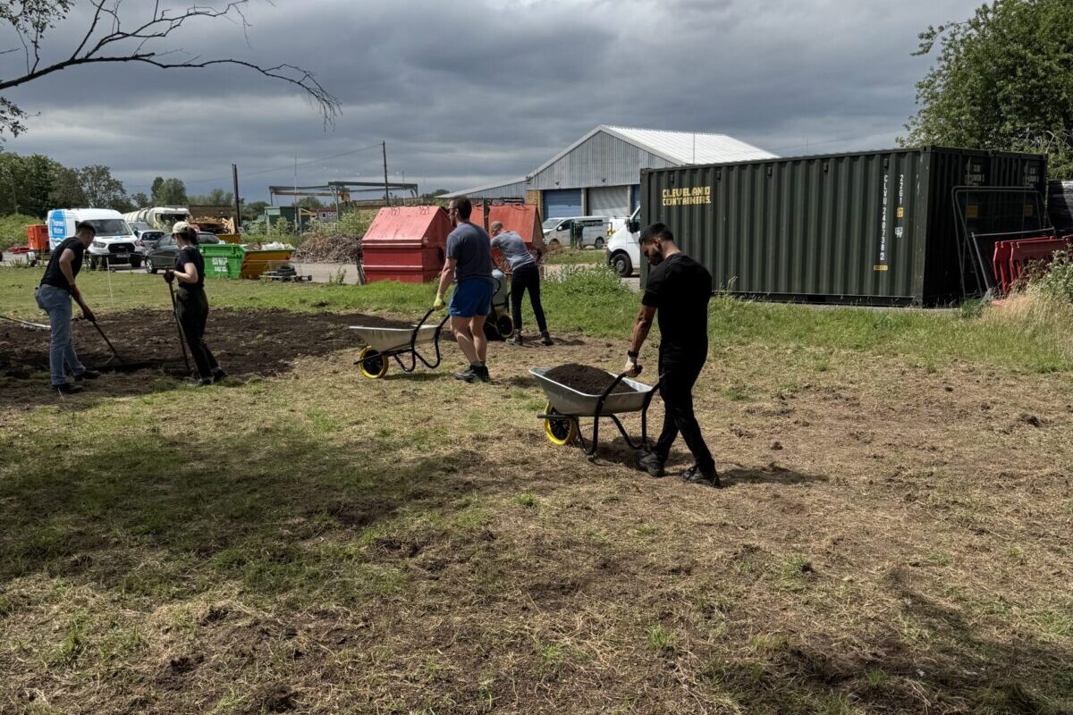 Volunteers wheelbarrowing soil to site