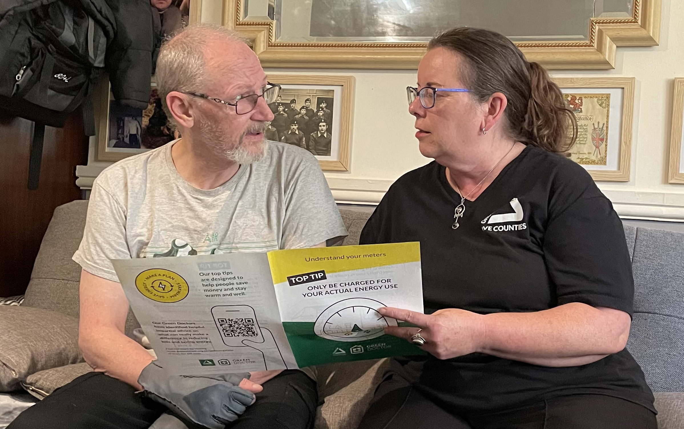 Man and woman sitting on sofa, the woman is holding a brochure with the headline 'only be charged for your actual energy use'