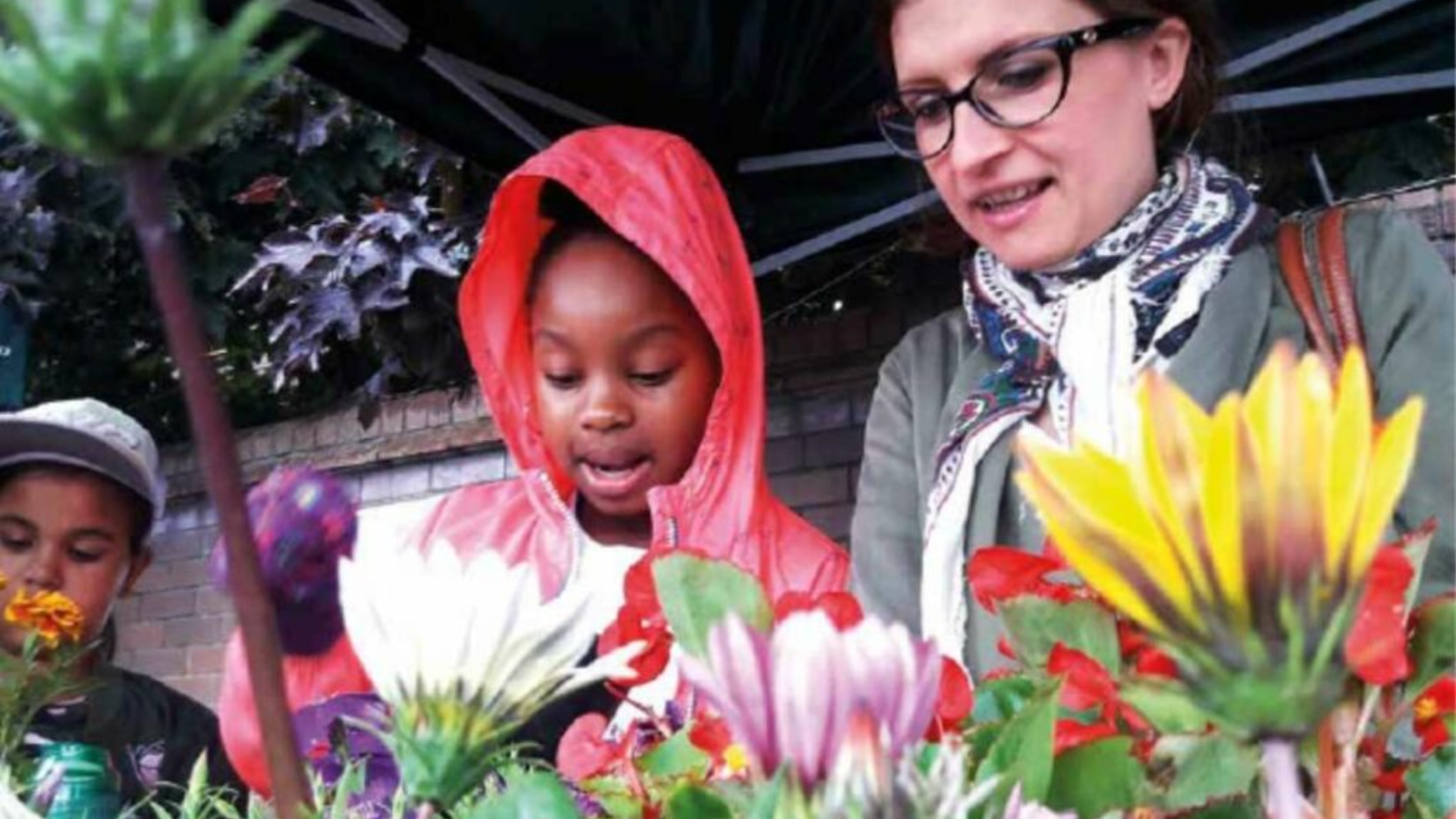 Picture of a woman and children in a park with flowers in foreground