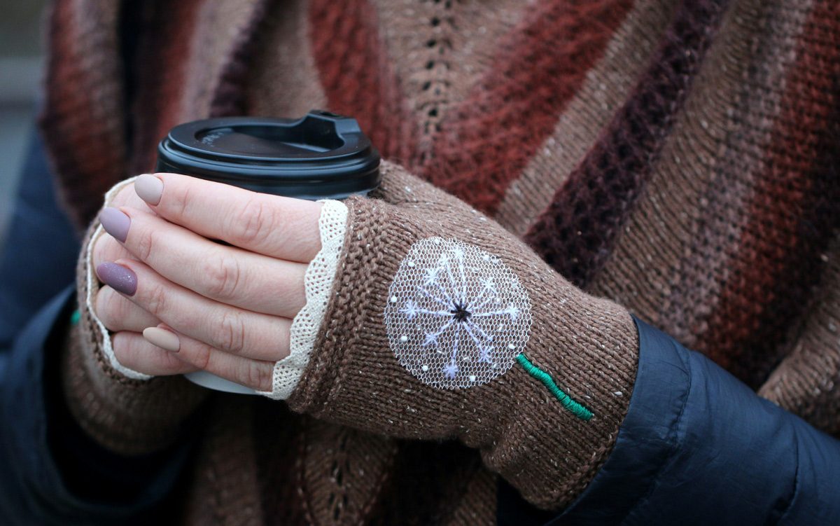 Person wearing brown gloves and scarf holding coffee cup